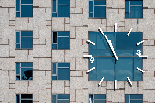 Barcelona, Spain - July 7, 2022: A view of an analog clock face on an exterior wall. The clock face shows 5 minutes to 11.
