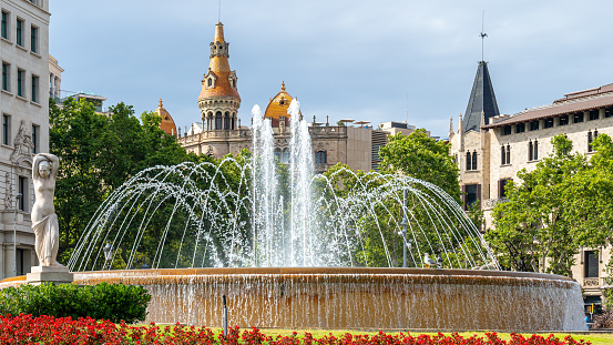 Barcelona, Spain - July 7, 2022: View of a beautiful water fountain in a city park. Flowers are around the water fountain, and no people are in the scene.