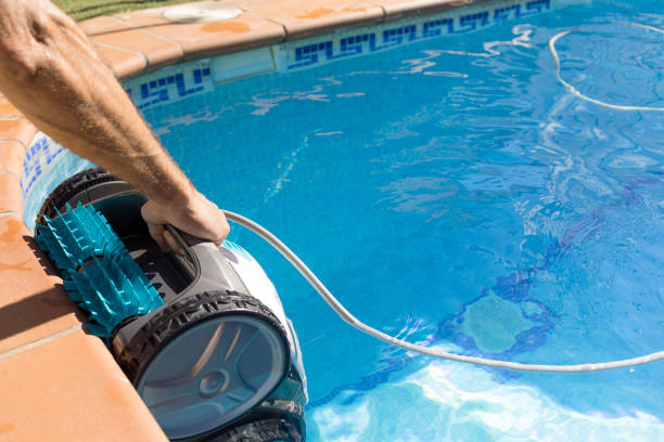 istock maintenance worker putting the cleaning robot into the pool water. robotic pool cleaner Pool maintenance with automatic robot. Cleaning the bottom of the pool and walls with a submersible robot. 1422500427