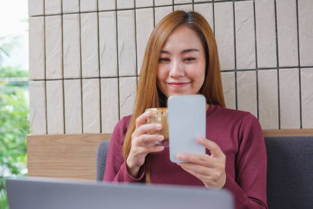 istock Portrait image of a woman holding and using smart phone and laptop computer while drinking coffee in office 1422504169