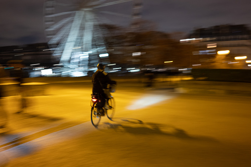 Blurred motion of a person on a bicycle with a Ferris wheel in the background
