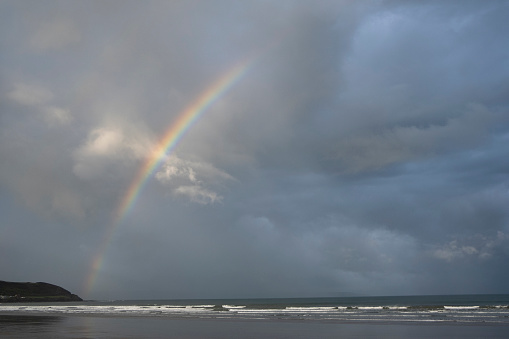 A rainbow forms over dramatic skies and beach in North Devon.