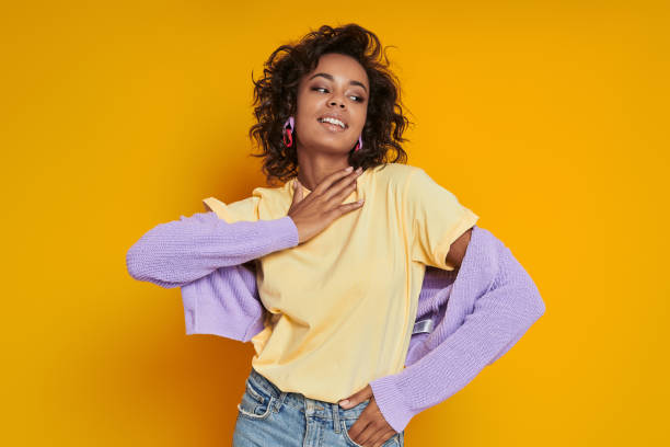 istock Stylish African woman smiling while standing against yellow background 1422513636