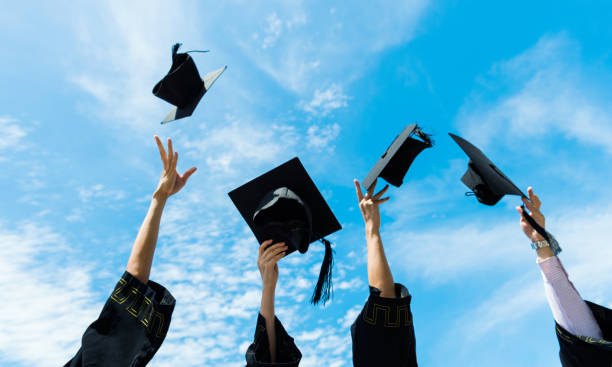 istock Four graduates throwing graduation hats in the air 1422516056