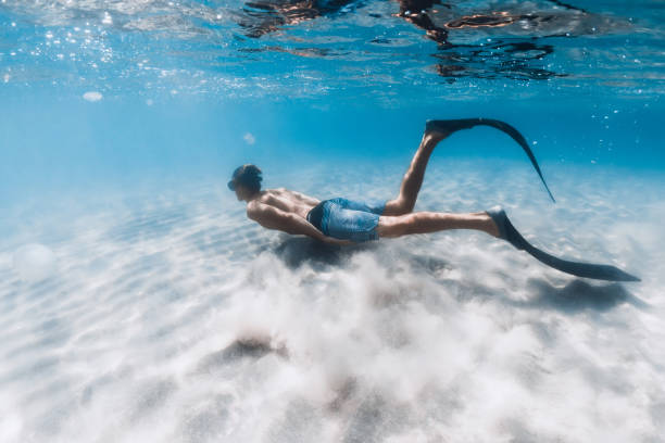 istock Free diver men swim underwater over sandy bottom in ocean 1422517317