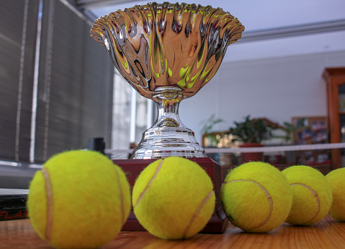 four tennis balls and a cup for the winner