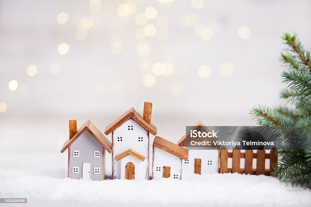 Happy New Year and Merry Christmas greeting card. Happy New Year and Merry Christmas greeting card. Toy wooden houses, spruce branches on the background of a beautiful bokeh. Christmas Stock Photo
