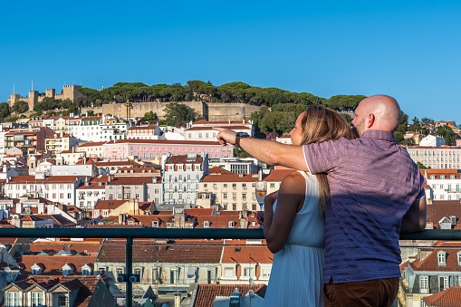 Couple visiting Lisbon and holding each other during a sunset of summer.