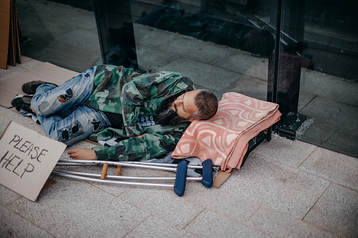 Poor homeless drunk man sleeping on the floor of the street on the background an empty bottle of wine. Barcelona, Catalonia, Spain 2019-04-30
