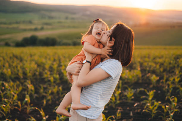 Portrait of a caucasian young mother and her daughter in a corn field hugging and kissing. Happy family, childhood. Mother nature. Happy family outdoors. Parent, child. stock photo