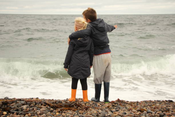 istock Boy and girl standing next to sea 1422552594