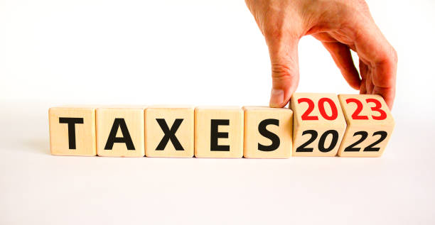 2023 taxes new year symbol. Businessman turns a wooden cube and changes words Taxes 2022 to Taxes 2023. Beautiful white table white background, copy space. Business 2023 taxes new year concept. stock photo