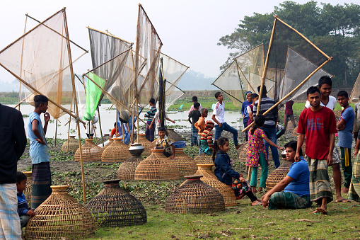 On special days of the year, villagers along with their relatives descend on the bill together for fishing. It is known locally as Polobawa Utsav (Fishing Ffestival) even though fishing is done using various materials including Polo and nets. Villagers wait by the lakeside before going down to the lake to catch fish. Sylhet, Bangladesh, 13 January 2018.