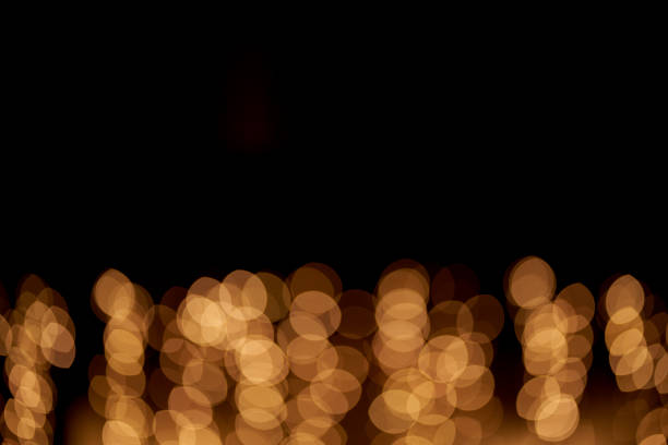 istock Abstract glowing bokeh lights highlighted on a black background. Festive golden glowing background with yellow lights. Overlay bokeh for your design. 1422561272