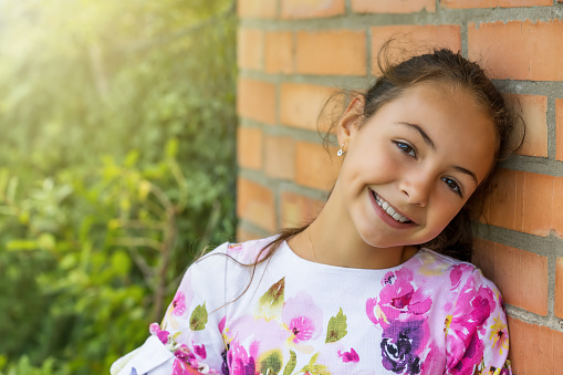 Pretty little girl is posing against a brick wall. Horizontally.