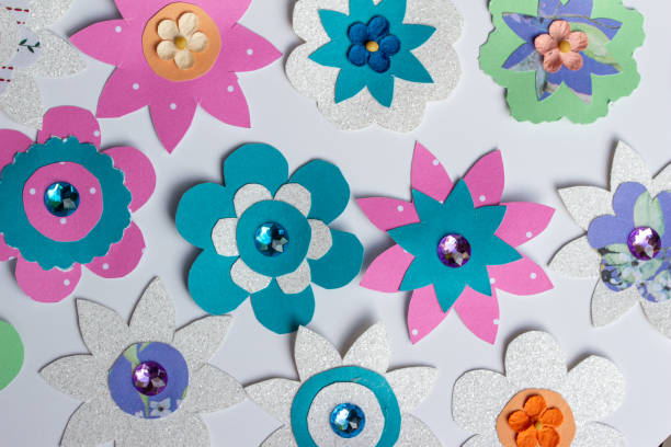 This image shows a full frame macro abstract texture design of colorful simply crafted paper flowers on a white background.