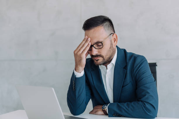 istock Stressed businessman having headache while working on laptop in the office. 1422565474