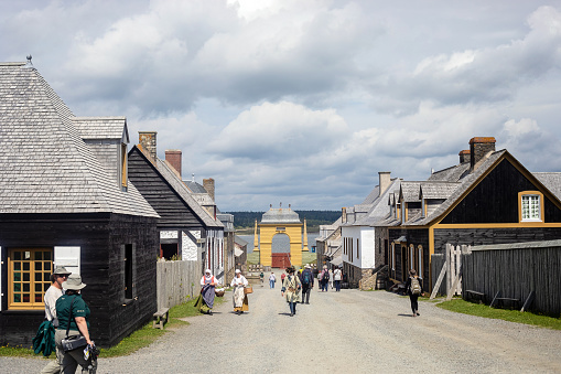 Louisbourg, Canada - August 27, 2022. Actors and tourists alike walk alongthe \n historic roads at the Fortress of Louisbourg.
