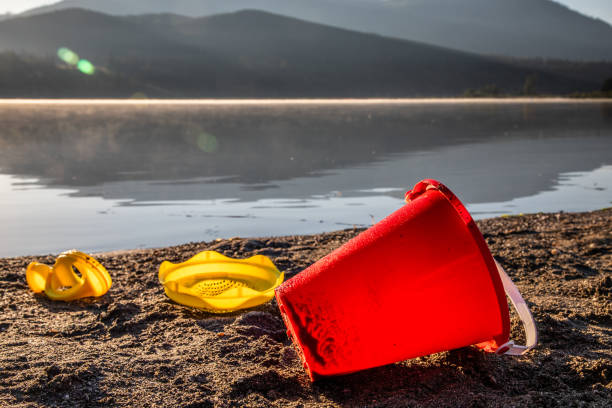 Early morning sunburst with an orange childs bucket in foreground on the sand