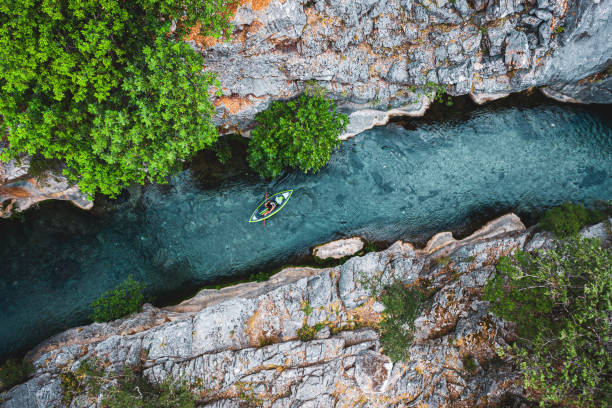 Aerial view of canoe athlete on river flowing in canyon overhead top view of kayak in canyon travel summertime activities on river . kayak surfing stock pictures, royalty-free photos & images