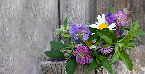 Colorful bouquet of meadow flowers on a wooden background with a place for text.