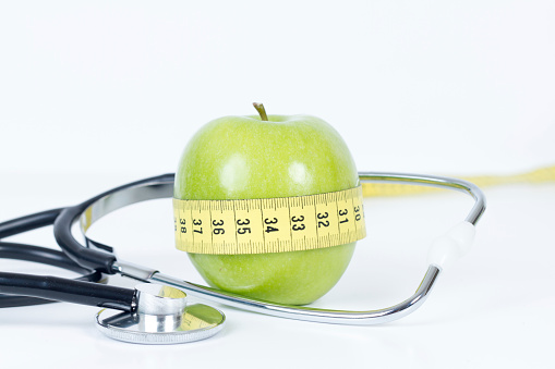 Fresh Green Apple Wrapped with Measure Tape and Stethoscope Isolated on White
