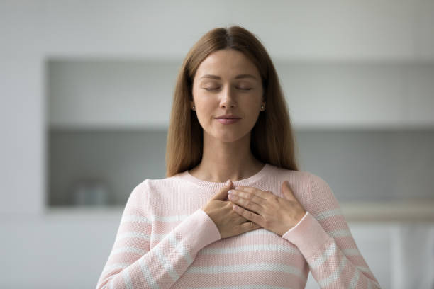 istock Peaceful beautiful Caucasian woman touching chest with both stacked hands 1422599552