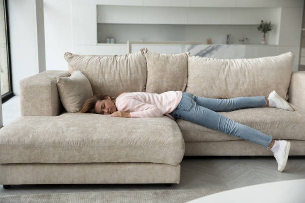 istock Sleeping young woman resting on home couch full length shot 1422599608