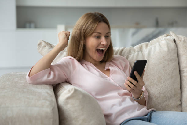 istock Cheerful excited mobile phone user woman staring at screen 1422599625