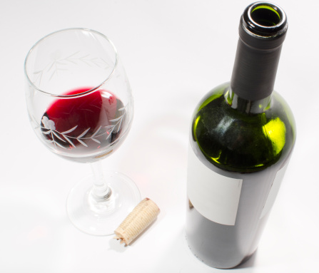 Studio shot of a uncorked bottle of wine  and a cup. Isolated on white.