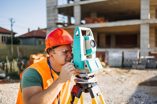 Land surveyor on a construction site, working with a total station.