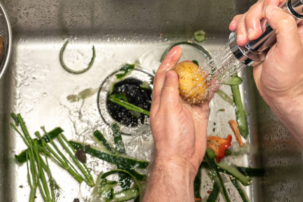 istock A man washes potatoes over a kitchen sink filled with waste from other vegetables. 1422605657