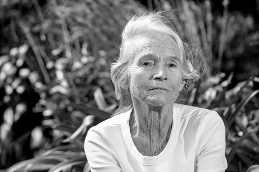 Black and white portrait of modern senior woman in the garden, background with copy space, full frame horizontal composition