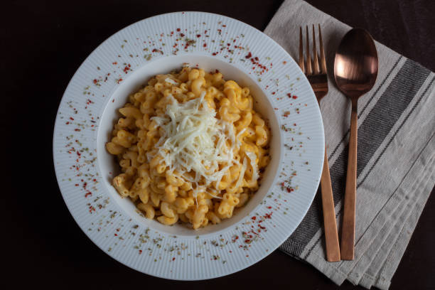istock Mac and cheese, american style macaroni pasta with cheesy sauce on dark rustic table, top view 1422611256