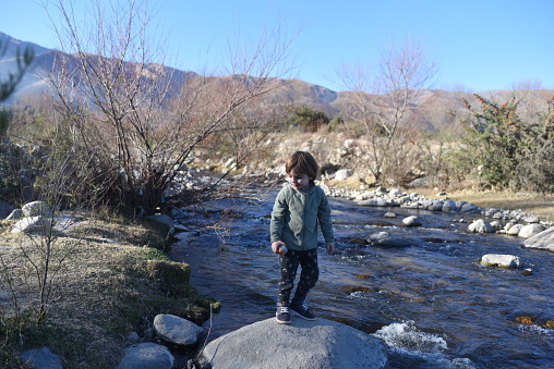 boy on a stone in a stream