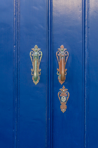 Blue wooden door with antique metal handles close up