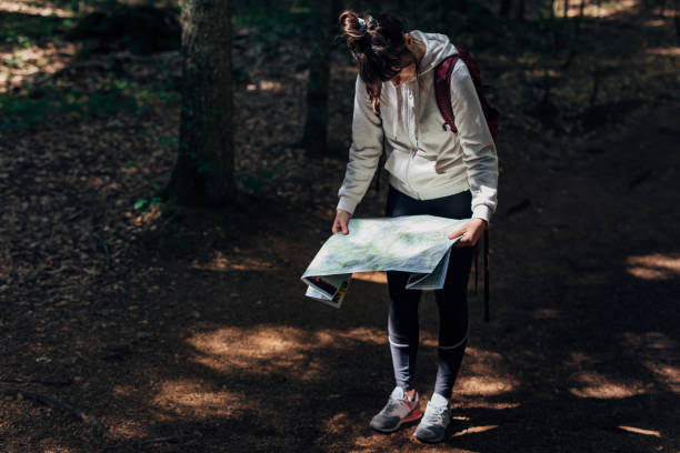 istock Young adventurous woman is looking the map while hiking through the mountain forest 1422614450