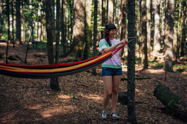 istock Young woman is tying her hammock to a tree in the forest. 1422614690