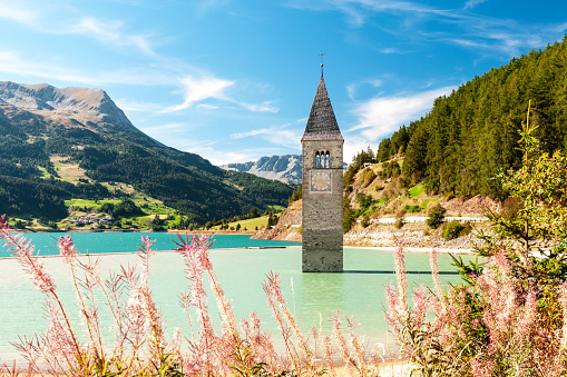 The famous bell tower in the Lake of Reschen - Lago di Resia - in South Tyrol, in Northern Italy. In 1950, a dam was build and put the village under water, only the tower is still visible now.