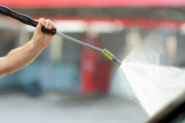 Car washing. Mature caucasian man cleaning automobile using high pressure jet water.
