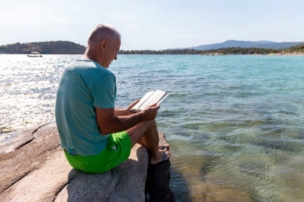 istock A man is reading a book next to the sea 1422626976