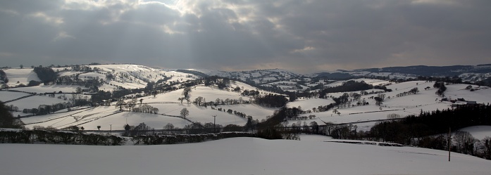 Sunlight on the hills of Powys in the snow near Llanyfillin, Wales.
