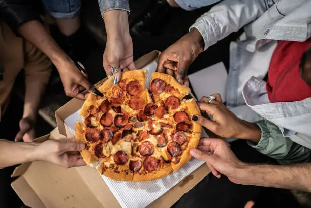 Photo of Hands picking pizza slices