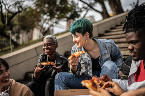 friends eating pizza in the park - pizza eating african descent lunch imagens e fotografias de stock