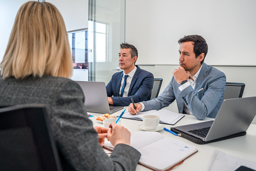 Male and female senior managers sitting down during an important interactive meeting in the conference room of a successful corporation