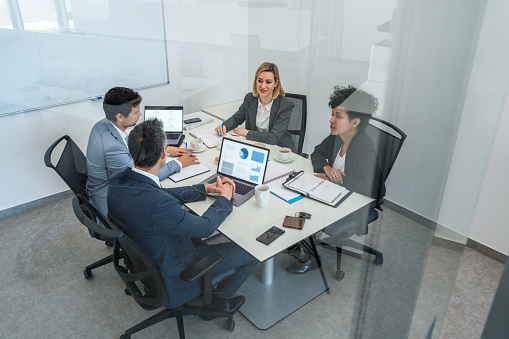 Photo of diverse group of business professionals discussing new plans during their meeting in the boardroom.