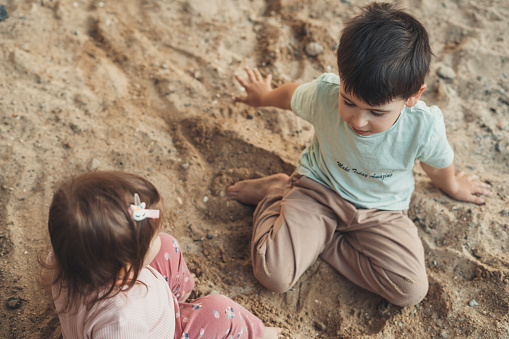 Top view of two little kids playing the sand, outdoor freeplay for kid development and social skill for childhood. Baby development. Preschooler outdoor. Active kid playing outdoors. Happy family.
