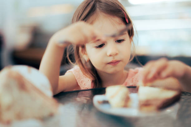 kleinkindmädchen, das sich darauf konzentriert, in einem restaurant zu essen - eating obsessive child toddler stock-fotos und bilder