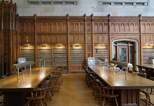 Ann Arbor, Michigan, USA - August 28, 2022:  University library reading room with elegant carved wood paneling and wooden tables.