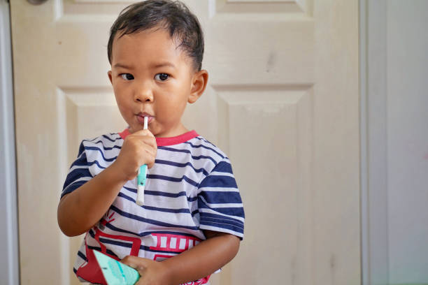 Kid brushing teeth. Kids toothbrush and paste. Asian kid brushing his teeth in white bathroom. Dental and heath for children. stock photo